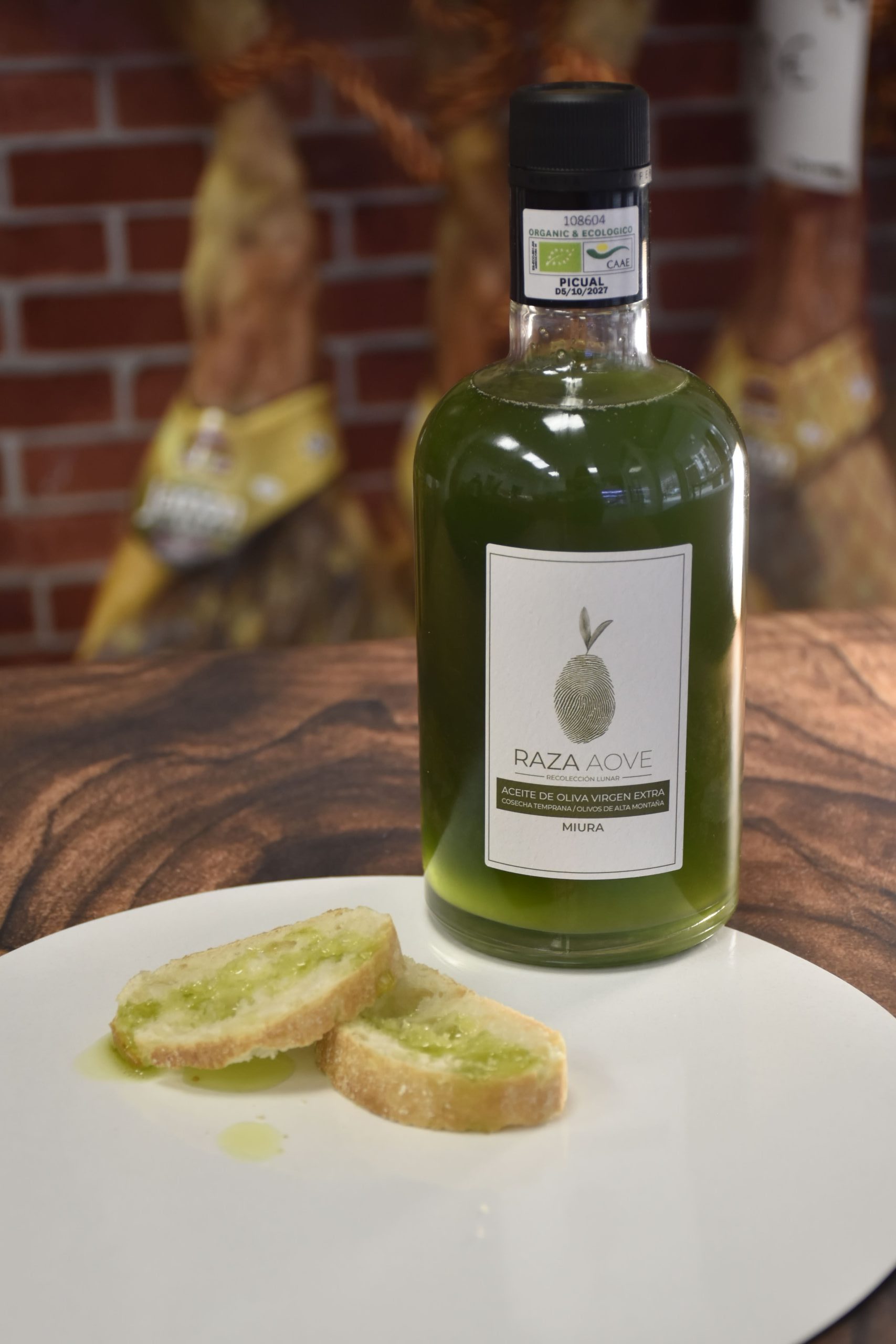 Botella de aceite de oliva virgen extra ecológico sin filtrar RAZA Miura Picual de 500 ml con pan mojado